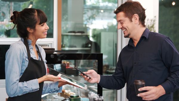 man using mobile payment in coffee shop