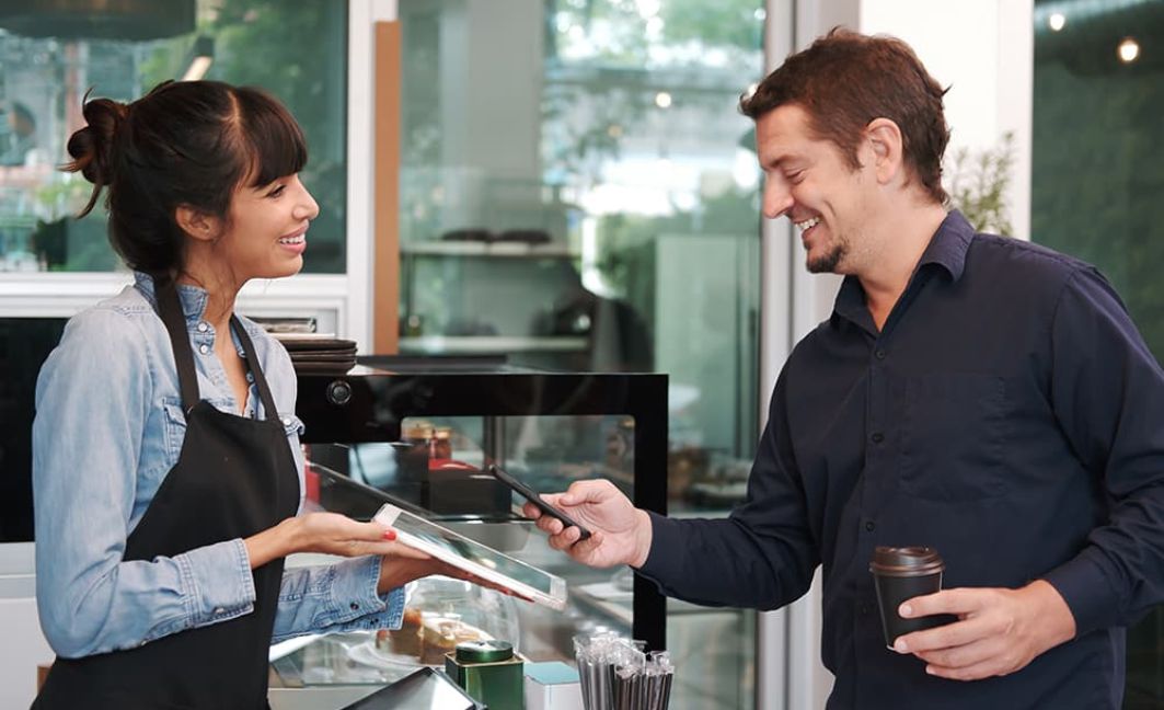 man using mobile payment in coffee shop